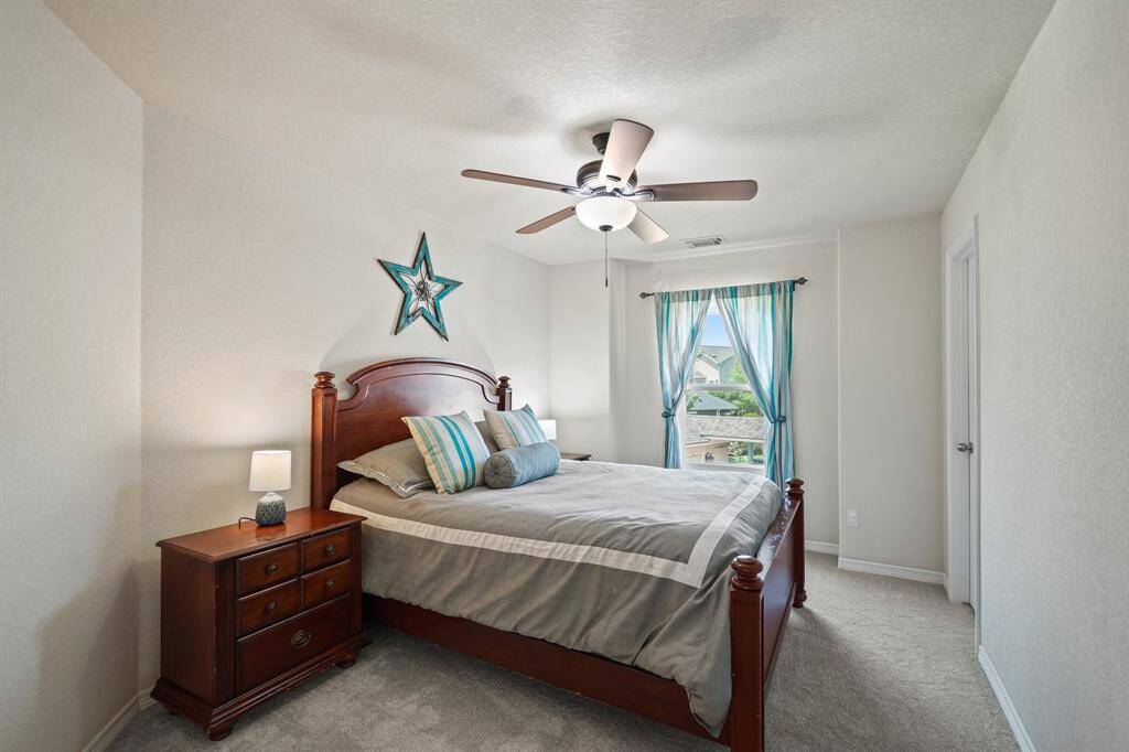 The fourth bedroom features a ceiling fan with light fixture, window with drapes, closet & carpet.