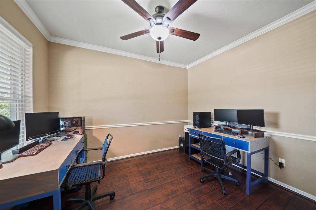 The private study with crown and chair rail moulding includes a ceiling fan with lighting & laminate hardwood flooring.