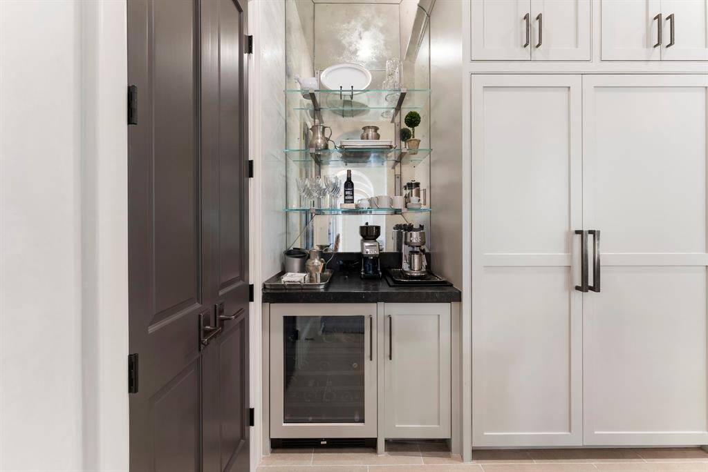 Adjacent to the kitchen is a versatile dry bar or coffee bar featuring a beverage fridge, with the walk-in pantry situated just to the left for easy access.