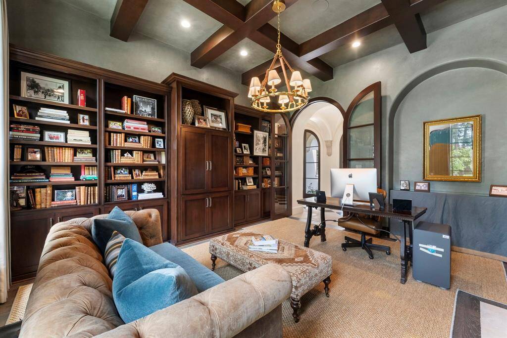 Elegantly appointed with arched French doors, wood beams, hardwood flooring, and bespoke built-ins, this study exudes timeless appeal.