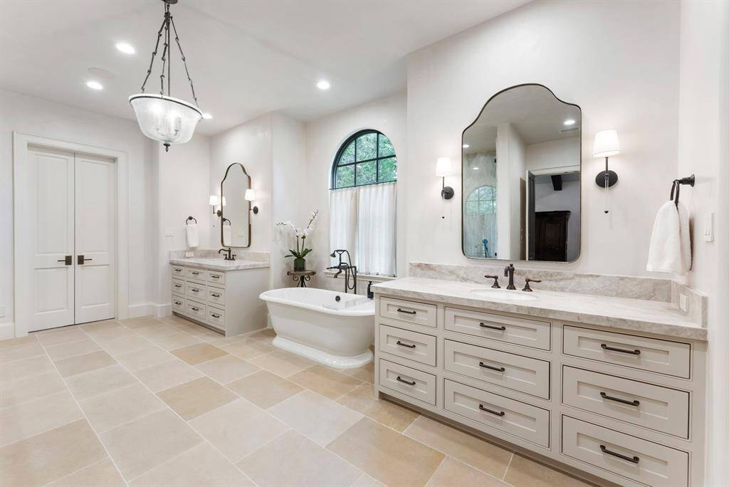 The luxurious en-suite bath showcases elegant stone flooring, dual leathered Perla Venata quartzite vanities, and custom cabinetry for a refined, spa-like experience.