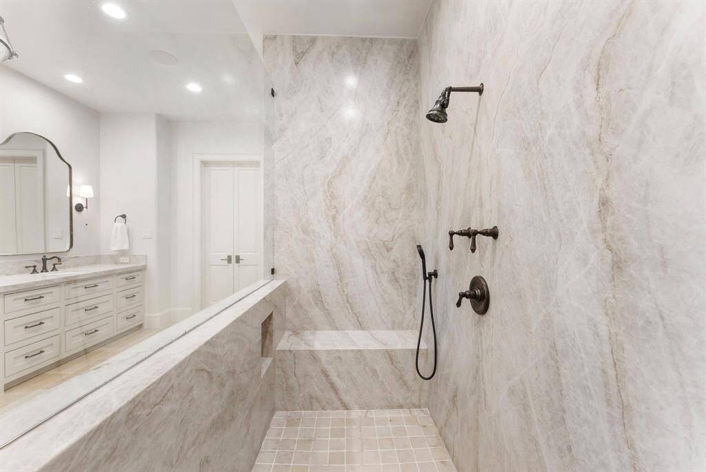 The oversized shower is a true standout, featuring leathered quartzite walls and a natural stone floor for a sleek, spa-inspired feel.