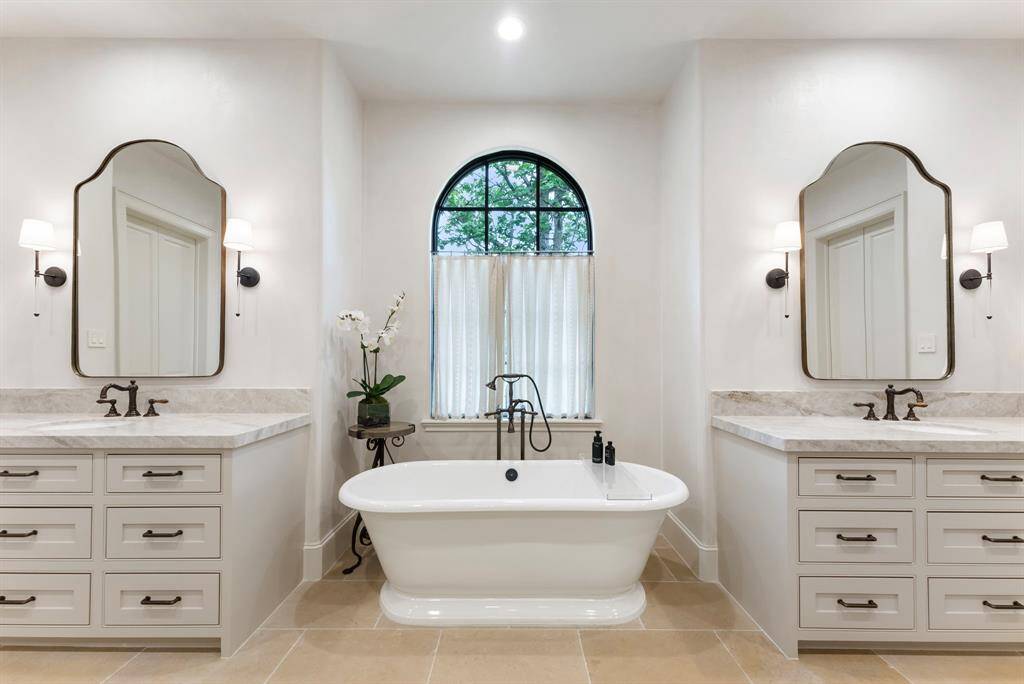 A serene soaking tub sits beneath a graceful arched window, offering a peaceful spot to unwind with natural light streaming in.