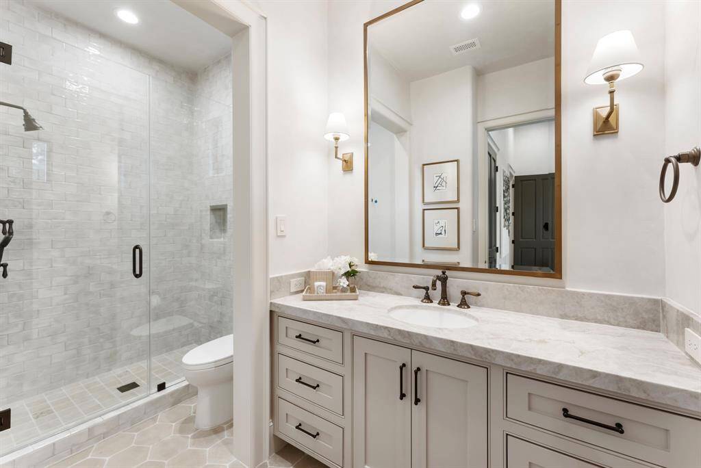 The en-suite bath features leathered Perla Venata quartzite countertops from Pomogranit and a walk-in shower adorned with elegant Watercolor Ceramic tile.