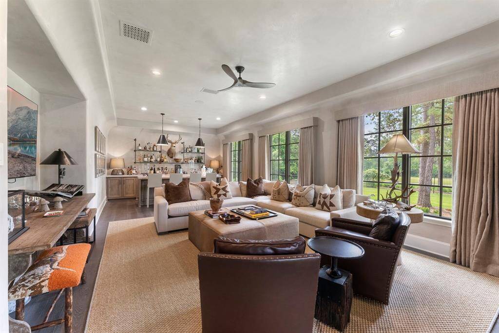 Designed for unforgettable gatherings, the downstairs game room impresses with its generous size, elegant tray ceiling, abundant natural light, and a custom bar.