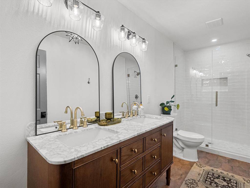 Fully updated primary en-suite boasts modern finishes, including a sleek dual vanity, stylish tilework, and a spacious walk-in shower.