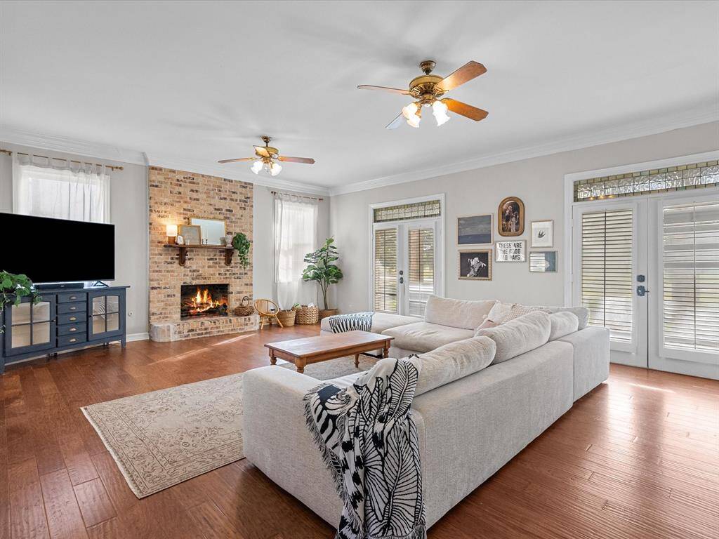 Stunningly spacious living room featuring a cozy fireplace and an abundance of natural light pouring in through six French doors