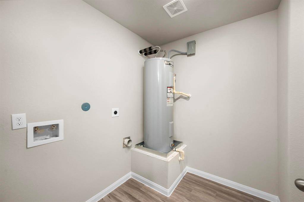 STAGED utility room with vinyl flooring and electric water heater.