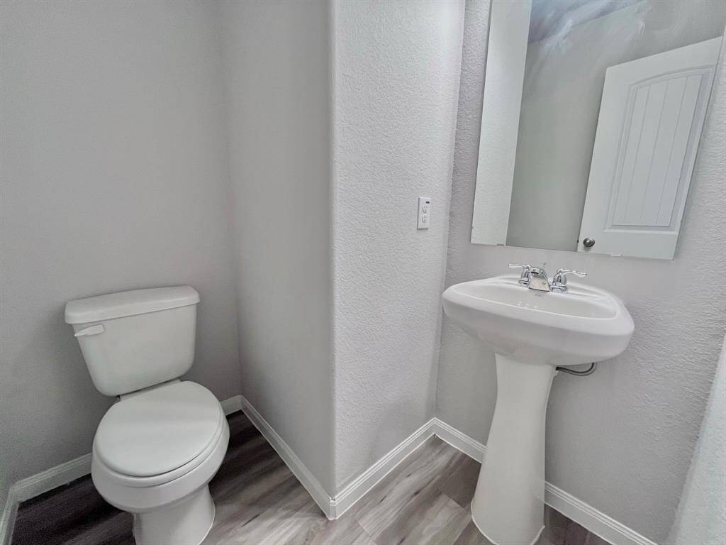 STAGED half bath downstairs next to utility room with vinyl flooring