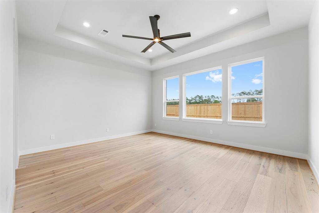 Primary Bedroom with Engineered Hardwood Flooring, Modern Fan, and 2 Walk-in Closets.