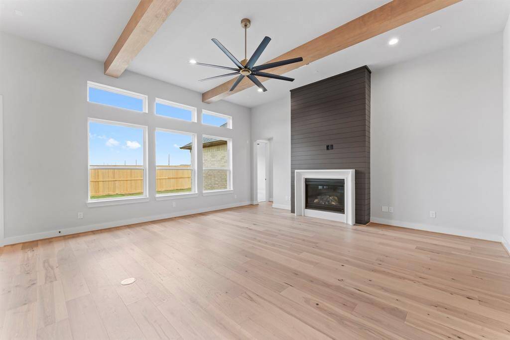 Family Room with Gas-Log Fireplace, Beams, Modern Fan and Floor Outlet.