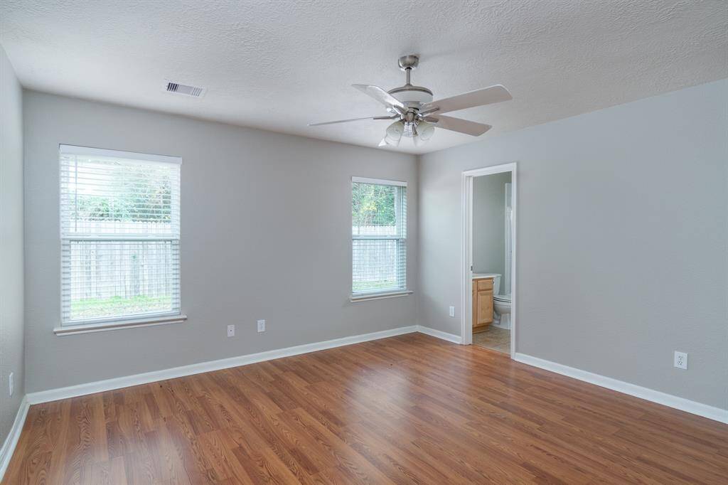 Large primary bedroom w/ ceiling fan, window coverings & walk-in closet!