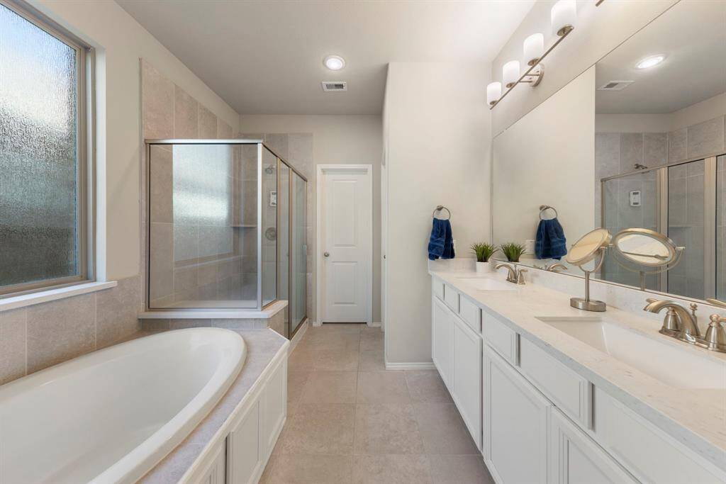 Sleek primary bath with dual sinks, oversized soaking tub, walk-in shower and huge walk-in closet.