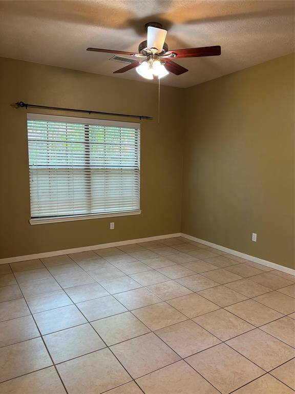 The dining room features a neutral color palette with tiled flooring, a ceiling fan, and a large window with blinds, offering a bright and airy feel.