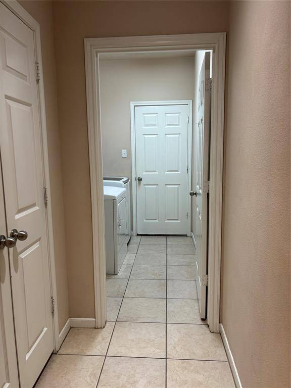 Hallway with tiled flooring leading to a laundry area.
