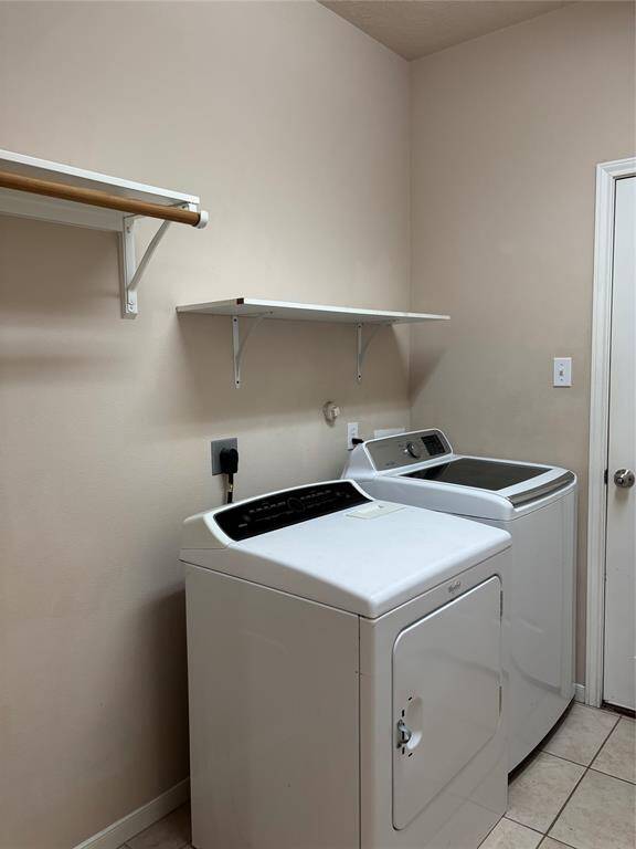 Laundry room featuring a washer and dryer, wall-mounted shelves.