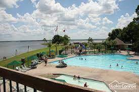 Community swimming pool area, surrounded by lounge chairs and a scenic view of the lake. Ideal for relaxation and outdoor enjoyment.
