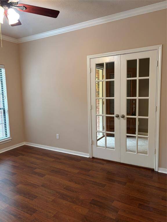 This room features warm wood flooring, neutral beige walls, and a ceiling fan. It includes French doors leading to front entry area, providing a classic look with plenty of natural light.