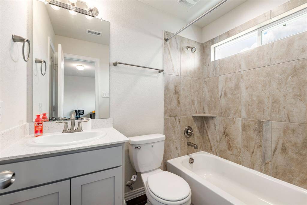 Secondary bathroom features light countertops and cabinets, custom paint, shower/tub combo with tile surround, large mirror, tile floors, sleek fixtures and modern finishes, plenty of space to accommodate any visiting family or guests.