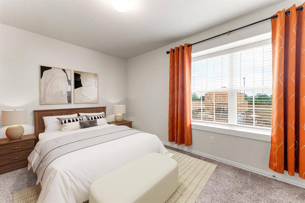 Secondary bedroom features plush carpet, custom paint, dark stained ceiling fan with lighting and a large window with privacy blinds. *Virtually Staged