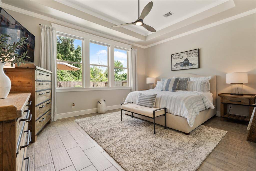 Relax and unwind at the end of a long day in the comfort of this serene Primary Retreat. The space boasts calming hues, a trey ceiling, crown molding, and a continuation of the wood-look tile flooring.