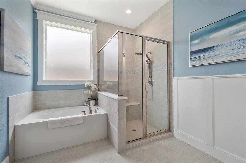Wash away the stress of the day in this spacious shower and garden tub. The tile runs from floor to ceiling, elongating the space. The shower includes a stationary and detachable shower head, quartz topped bench, and decorative tile accent.  A cased picture window allows natural light to fill the space without compromising on privacy.
