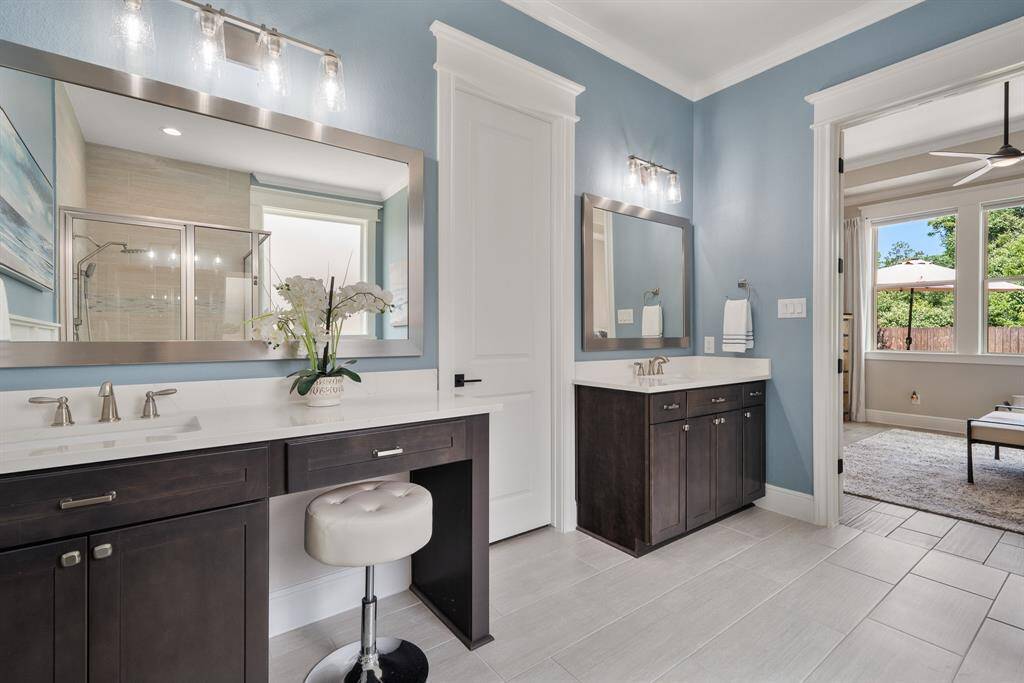 The Primary Bath is finished with cased openings, crown molding, custom framed mirrors, and a spacious walk-in closet. Both vanities boast undermount sinks, quartz countertops, and stained wood cabinets.