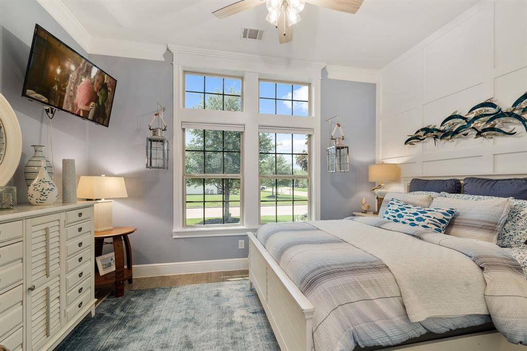 This Secondary Bedroom is located directly off the Foyer and boasts a framed accent wall, crown molding, and walk-in closet. The pair of windows, with transoms above, overlook the Front Yard, and are flanked by two hanging carriage lights. This Bedroom has direct access to the Full Bath across the hall.