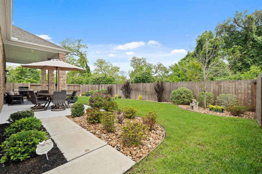 The Backyard is fully fenced and boasts an abundance of low maintenance, but high appeal, plants, trees, and shrubs. The bull rock filled beds aid in drainage and cut down on weeds. Notice how a canopy of trees is seen sitting just above the fence line!