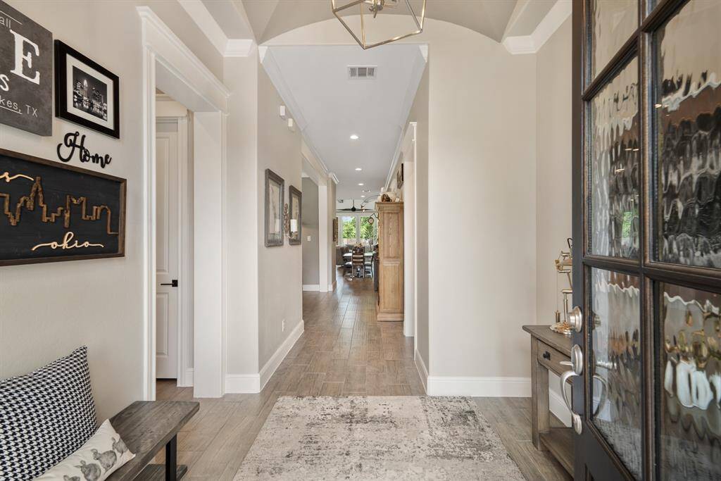 What a warm and inviting first impression! The Foyer boasts neutral toned wood-look tile flooring, an accentuated groin vault ceiling, crown molding, and high-end chandelier. The eyes are immediately drawn towards the back of the home and the lush Backyard beyond.