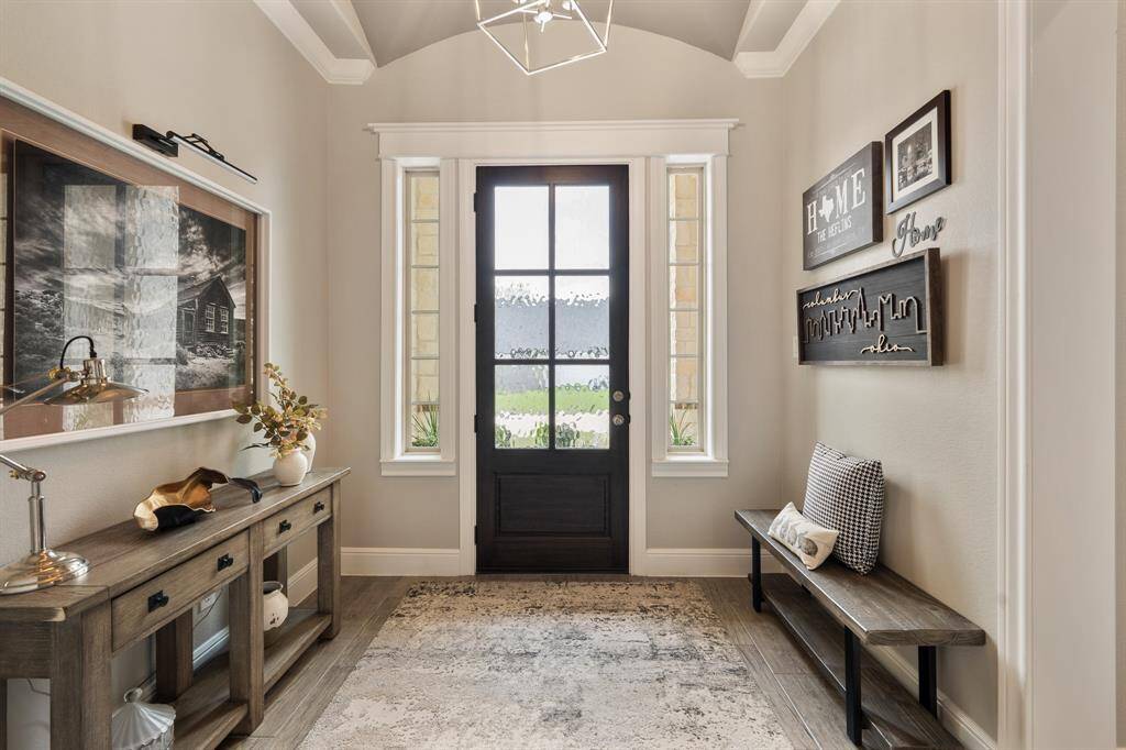 This look back towards the beautiful, glass-plated front door shows just how sizeable the space is, easily accommodating a storage piece and bench seat. A museum light allows you to display your favorite piece of art where everyone can see it, day or night.