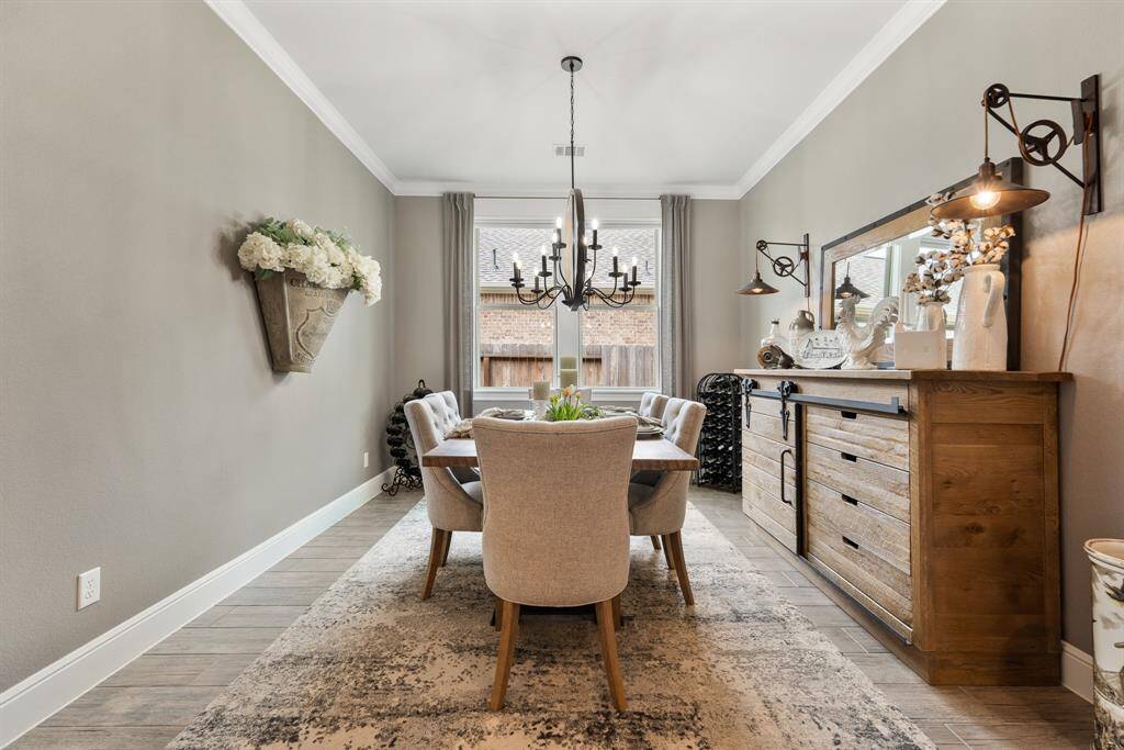 The Dining Room, located right off the Foyer, is bathed in a neutral cashmere color that blends perfectly with the wood-look tile flooring below, while making the white, oversized baseboards and crown molding really pop.