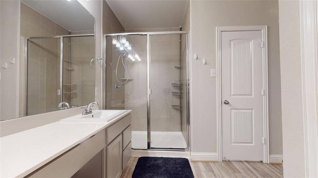Elegant primary bathroom featuring a sleek shower and spacious walk-in closet.