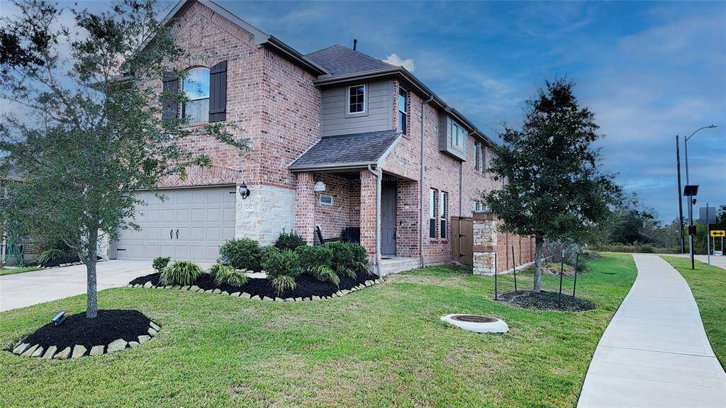 Charming brick home with a spacious two-car garage, lush landscaping, and inviting curb appeal.