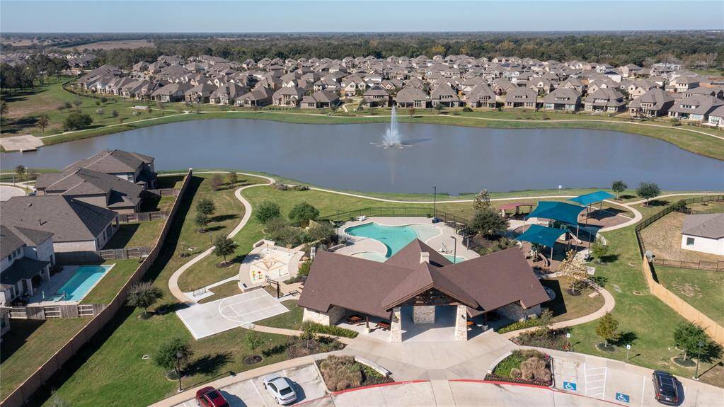 Stunning aerial view of a serene community pool, nestled by a picturesque lake, offering a perfect blend of relaxation and scenic beauty.