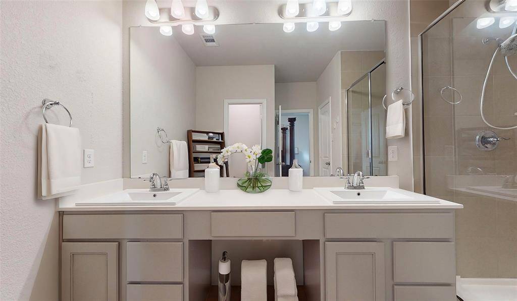Virtually staged primary bathroom showcases a modern double vanity, elegant fixtures, and a spacious shower, creating a fresh and inviting atmosphere.