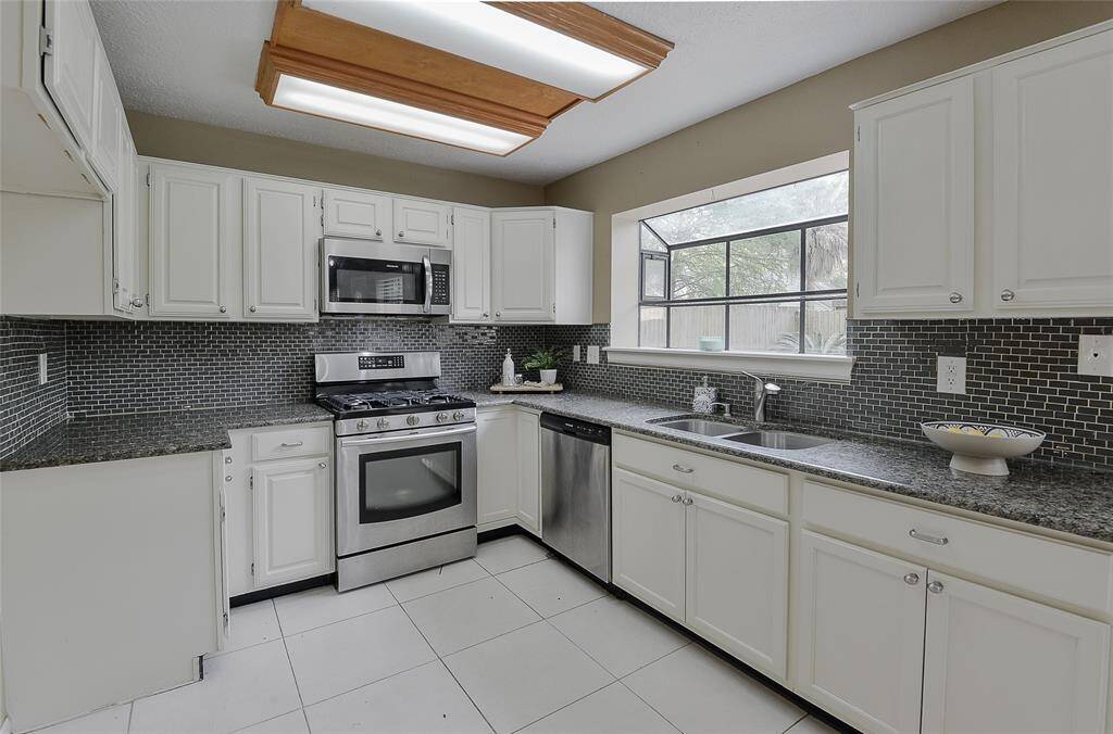 Kitchen features white cabinets, granite countertops, and tile backsplash.