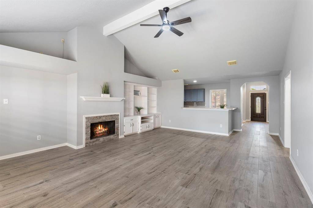 Open living room with soaring ceilings, a warm fireplace, and a built-in entertainment center is perfect for relaxing with family.