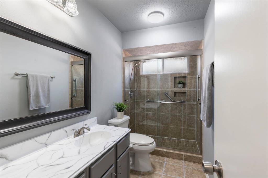Well-appointed secondary bathroom features a large walk-in shower, generous counter space, and plenty of cabinet storage.