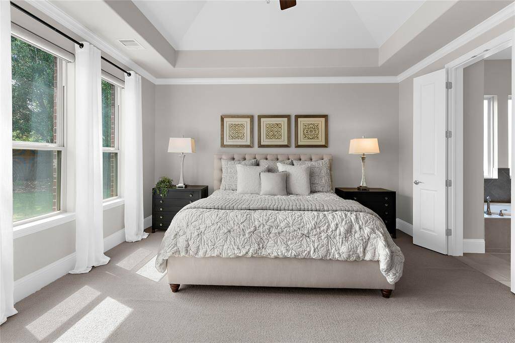 This primary bedroom has vaulted high ceilings and double doors to the  master ensuite.