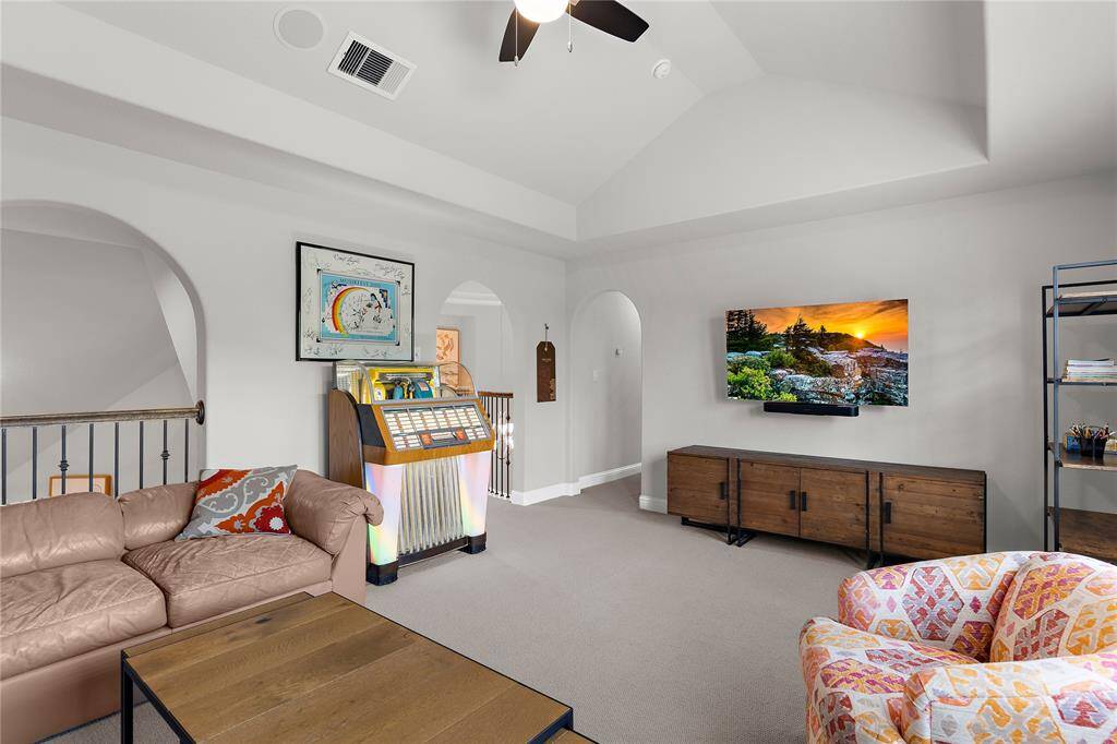 Another angle of the game room upstairs with vaulted ceilings and fan.