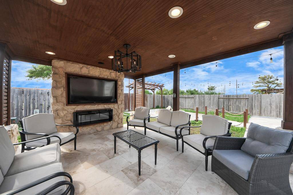 The backyard patio, complete with a cozy fireplace and mounted TV, creates the perfect setting for outdoor entertaining and relaxation.