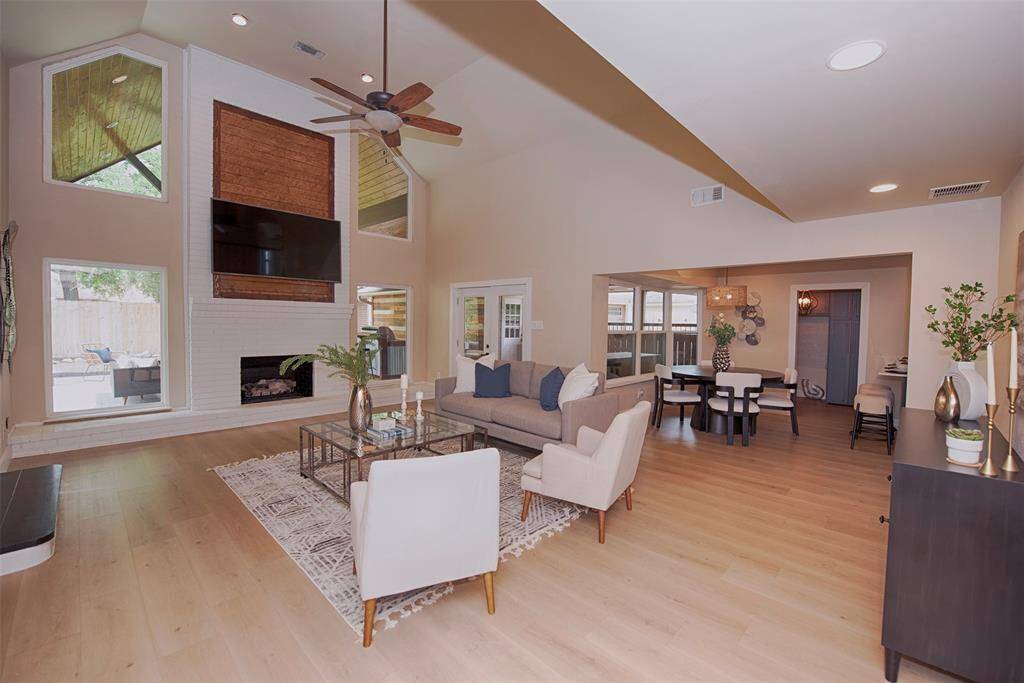 Entry from the foyer to large family room with soaring ceiling, gorgeous luxury vinyl floors, gas log fireplace and incredible space.