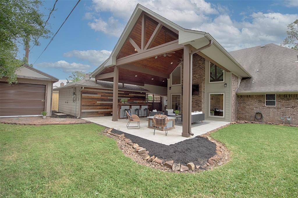 A view of the back patio showing the stunning architecture which has a stone accented garden to add a pop of color.