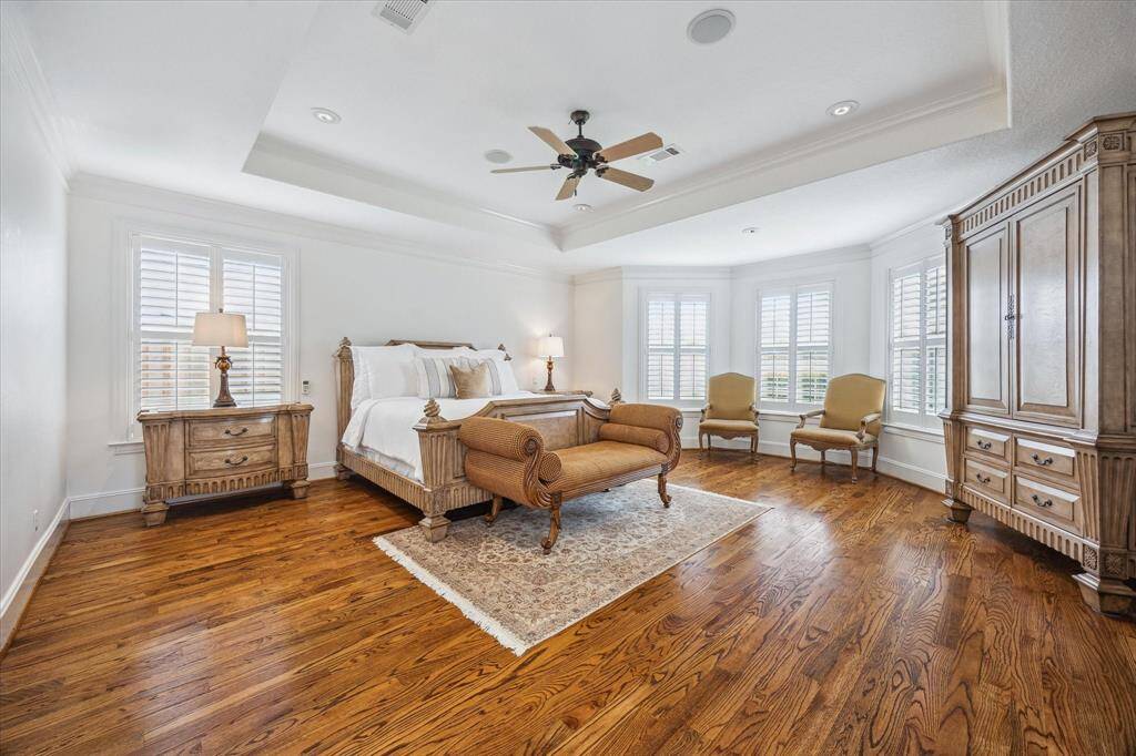Serene private primary suite located on the 1st floor offers coffered ceilings, sitting area with windows overlooking backyard, private access to pool, and ensuite bath.