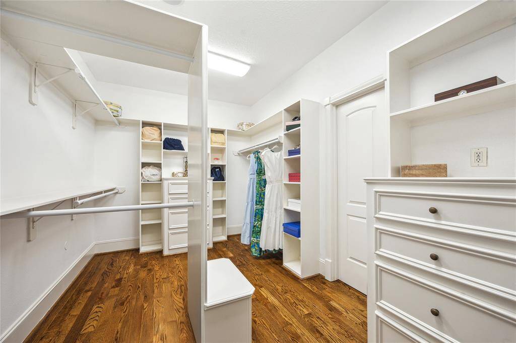 Spacious primary walk-in closet offers built-in dressers, shelving and double hang.