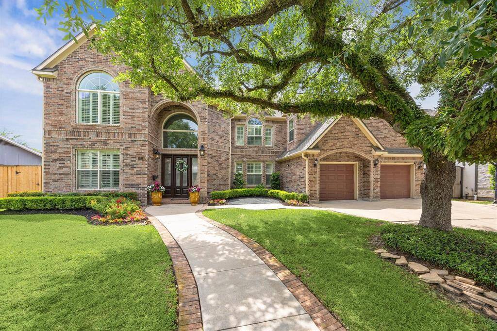 Professionally landscaped front yard framed by its own majestic tree with brick surround walkway to entrance. Oversized driveway with double garage doors.