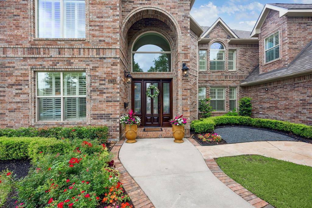Entry offers glass Mahogony front door with 2 story arched transom and brick accented windows.