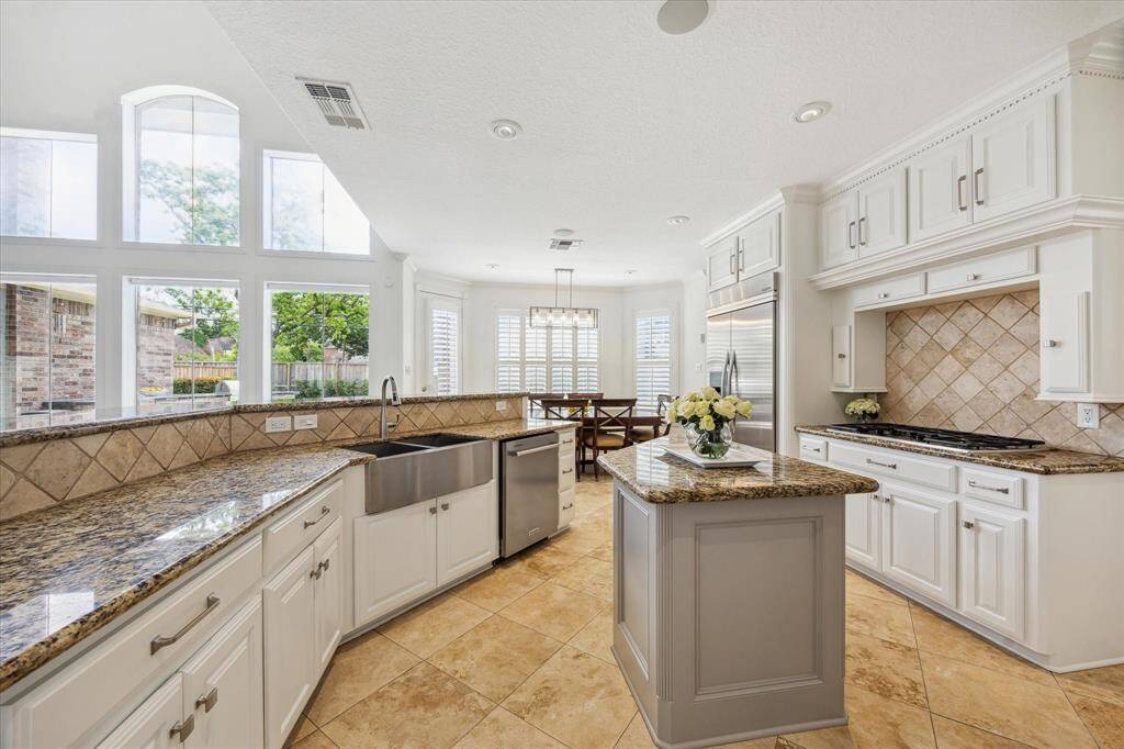 Kitchen features stainless double sink, stainless double electric convectional ovens, gas cooktop, stainless dishwasher and built-in refrigerator.