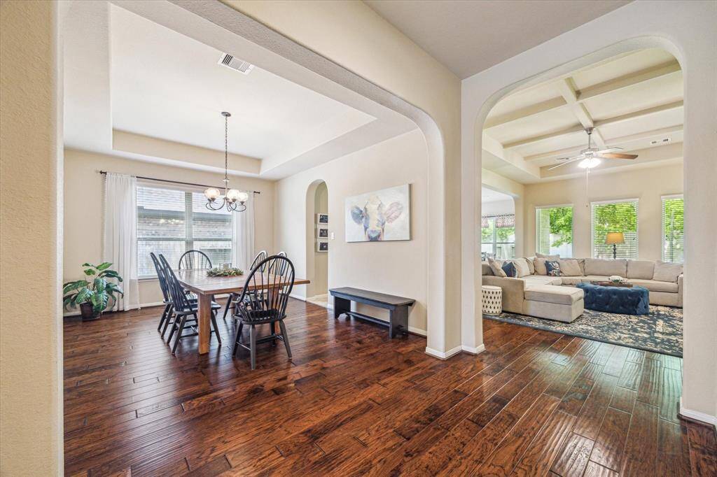 The open, airy floor plan invites you to come in, relax, and stay a while. It features a spacious formal dining room with a raised tray ceiling and a cozy family room anchored by a beautiful coffered ceiling and a warm, inviting fireplace perfect for both gatherings and quiet evenings at home.